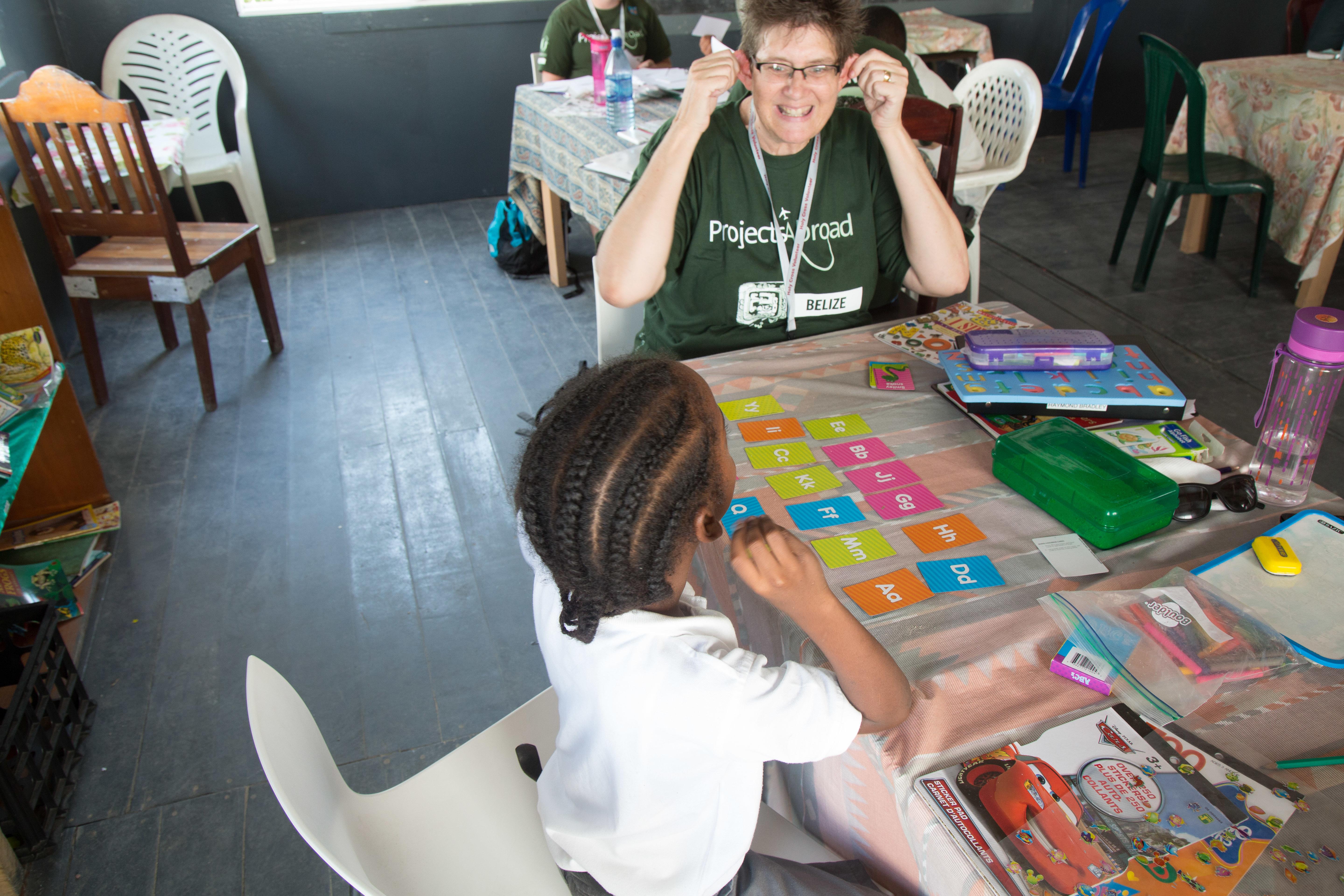 Projects Abroad volunteer teaching English spelling to a student in Belize A young girl learns the alphabet during at a volunteer teaching placement in Belize